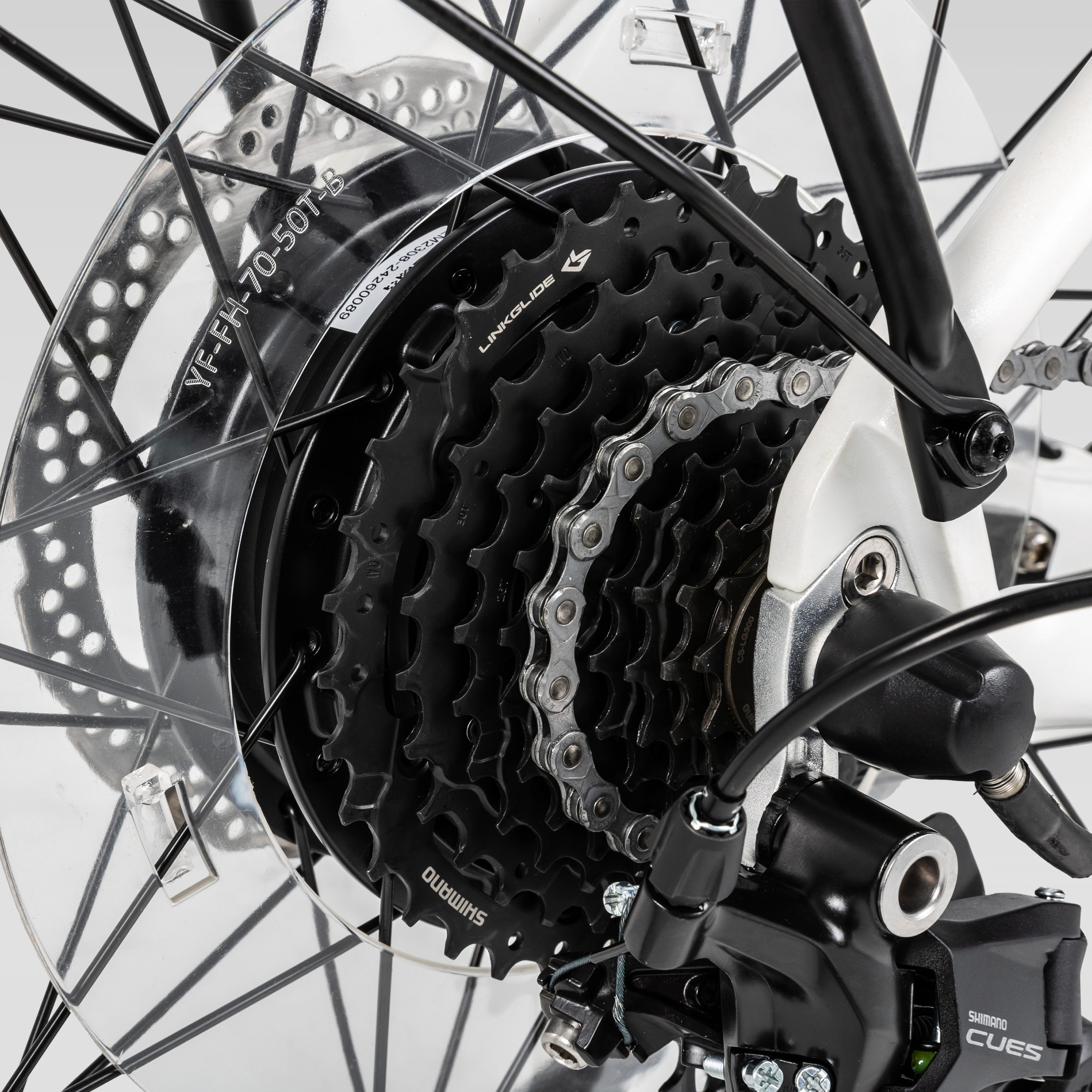 Close-up of bicycle rear wheel showing Shimano cassette, chain, and derailleur components in black and white