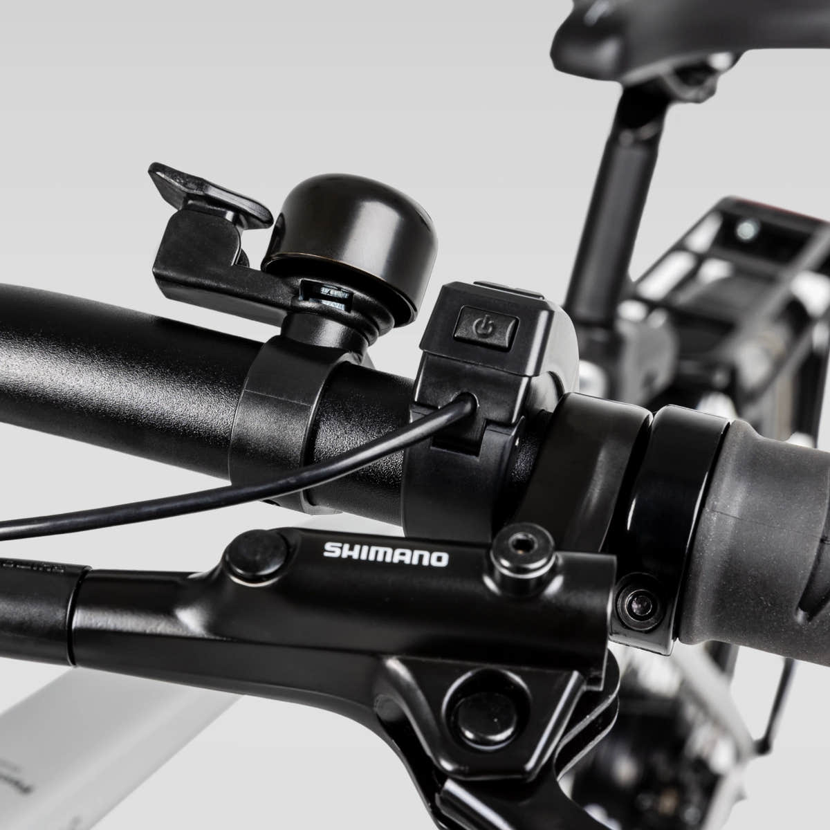 Left handlebar on the Cement Gray Urban Cruise showing the Shimano brake lever, bell, and control switch